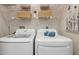 Well-organized laundry room featuring newer washer, dryer, and overhead shelving at 2387 Hanover Dr # 2387, Dunedin, FL 34698