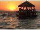 Tiki bar on a floating barge drifts on calm seas against the colors of a vivid sunset at 2387 Hanover Dr # 2387, Dunedin, FL 34698