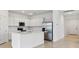 Modern kitchen featuring a large island, stainless steel appliances, and sleek white cabinets at 2760 Winding Creek Trl, North Port, FL 34289