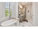 Bright main bathroom featuring a soaking tub, vanity with storage, and natural light from a large window at 3607 W Roland St, Tampa, FL 33609