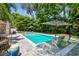 Landscaped backyard with pool, sun loungers, and comfortable lounge chairs and umbrella at 3607 W Roland St, Tampa, FL 33609