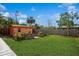 A spacious backyard with grass, shed, garden, wooden fence, and green foliage at 413 Blackburn Rd, Nokomis, FL 34275