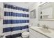 Well-maintained bathroom featuring a vanity with sink, toilet, and bathtub with stylish blue striped curtain at 4902 Blue Heron Dr, New Port Richey, FL 34652