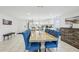Bright dining room features a large wooden table with blue tufted chairs and white tile floors at 4902 Blue Heron Dr, New Port Richey, FL 34652