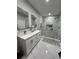 Modern bathroom featuring dual sinks, marble tile, and glass-enclosed shower with gold trim and fixtures at 5180 69Th N Ave, Pinellas Park, FL 33781