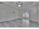 Bright bedroom featuring tray ceiling, ceiling fan, sliding glass door to the lanai, and stylish gray wood-look floors at 5814 Stockport St, Riverview, FL 33578