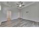 Bright bedroom featuring tray ceiling, ceiling fan, stylish gray wood-look floors, and multiple entry doors at 5814 Stockport St, Riverview, FL 33578