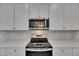 Modern kitchen featuring stainless steel oven and microwave against decorative back splash and white cabinetry at 5814 Stockport St, Riverview, FL 33578