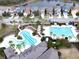 Aerial view showcasing community pools surrounded by palm trees and homes with a lake in the background at 7869 Timberview Loop, Wesley Chapel, FL 33545
