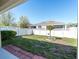 View of the backyard featuring a white fence, small tree, grass, and patio area from underneath covered patio at 7869 Timberview Loop, Wesley Chapel, FL 33545