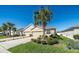 Well-manicured home exterior showcasing a long driveway, three-car garage, mature landscaping, and a lush lawn at 7869 Timberview Loop, Wesley Chapel, FL 33545