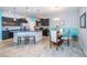 Modern kitchen featuring stainless steel appliances, black cabinetry, an island with bar seating, and dining table at 7869 Timberview Loop, Wesley Chapel, FL 33545