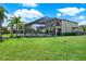 Backyard view of the home showcasing the screened-in pool and lush green lawn at 8420 Dunham Station Dr, Tampa, FL 33647