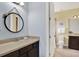 Cozy bathroom featuring a round mirror and dark wood vanity with stone countertop at 8420 Dunham Station Dr, Tampa, FL 33647