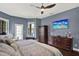 Comfortable bedroom boasts a ceiling fan, television, and traditional wood furnishings at 8420 Dunham Station Dr, Tampa, FL 33647