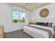 Cozy bedroom featuring a stylish chandelier, a comfortable bed, and a view through a large window at 9740 Redwood Heights Loop, Thonotosassa, FL 33592