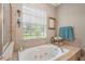 Bright bathroom features a soaking tub with jets, natural light from the window, and decorative shelving at 9916 Preakness Stakes Way, Dade City, FL 33525