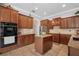 Spacious kitchen featuring tile flooring, wooden cabinetry, stainless steel appliances, and a center island at 9916 Preakness Stakes Way, Dade City, FL 33525