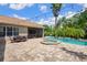 A spacious backyard featuring a pool, spa, brick pavers, outdoor dining, and lush tropical landscaping, perfect for entertaining at 9916 Preakness Stakes Way, Dade City, FL 33525
