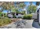 Single-story home featuring a driveway bordered by mature trees and garden at 12116 N 52Nd St, Temple Terrace, FL 33617