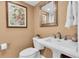 Stylish powder room with a pedestal sink, framed mirror, and floral artwork at 12274 1St W St # 2, Treasure Island, FL 33706