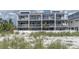 Townhouse exterior with multiple balconies, white railings, and beach access with dune vegetation at 12274 1St W St # 2, Treasure Island, FL 33706