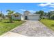 Two-story home featuring a three-car garage, manicured lawn, and a patterned brick driveway at 12546 Wildebeest Way, Spring Hill, FL 34610