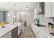Galley kitchen featuring white cabinets, quartz countertops, stainless steel appliances, and a farmhouse sink at 12546 Wildebeest Way, Spring Hill, FL 34610