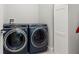 Laundry room with modern, front-loading washer and dryer and extra cabinet at 12546 Wildebeest Way, Spring Hill, FL 34610