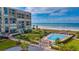 Stunning aerial view of a beachfront condo complex with a pool, palm trees, and ocean access at 1430 Gulf Blvd # 102, Clearwater Beach, FL 33767