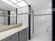 Bright bathroom featuring tiled walls, a vanity with a large mirror, and a shower with accessibility features at 1430 Gulf Blvd # 102, Clearwater Beach, FL 33767