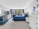 Bright bedroom featuring a comfortable bed, white dressers, and a cozy blue seating area at 1430 Gulf Blvd # 102, Clearwater Beach, FL 33767