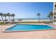 Large pool with tiled patio, beach views and tropical umbrellas and greenery at 1460 Gulf Blvd # 406, Clearwater Beach, FL 33767