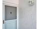Close up of unit 140's exterior white front door and hardware with stucco exterior at 1655 S Highland Ave # D140, Clearwater, FL 33756