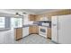 Kitchen featuring light wood cabinets, white appliances and a breakfast bar at 1655 S Highland Ave # D140, Clearwater, FL 33756