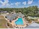 High-angle view of community pool, lounge chairs, and shuffleboard courts surrounded by mature trees and green spaces at 1655 S Highland Ave # D140, Clearwater, FL 33756