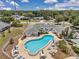 Aerial view of a community pool area with lounge seating, umbrellas, and shuffleboard courts in a residential setting at 1655 S Highland Ave # D140, Clearwater, FL 33756