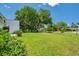 Wide shot of the grassy yard and shady trees behind the condo building exterior at 1655 S Highland Ave # D140, Clearwater, FL 33756