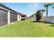Wide backyard with green grass, perimeter palm trees, and screened patio at 16840 Whisper Elm St, Wimauma, FL 33598