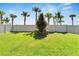 Well-maintained backyard with green grass, palm trees, and white fencing at 16840 Whisper Elm St, Wimauma, FL 33598