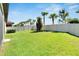 Wide backyard with green grass, perimeter palm trees, and white fencing at 16840 Whisper Elm St, Wimauma, FL 33598