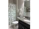Well lit bathroom features a granite countertop, decorative shower curtain, and tiled floor at 16840 Whisper Elm St, Wimauma, FL 33598