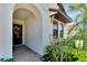 Inviting front entryway featuring a dark wood front door, brick flooring, and lush landscaping around the entrance at 16840 Whisper Elm St, Wimauma, FL 33598