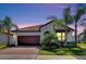 Charming single-story home featuring a brown tile roof, a spacious two-car garage, and a beautifully landscaped front yard with palm trees at 16840 Whisper Elm St, Wimauma, FL 33598