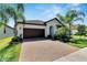 Beautiful one-story home with a well-maintained brick driveway, mature landscaping, and a brown tile roof on a sunny day at 16840 Whisper Elm St, Wimauma, FL 33598