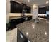 Close-up on kitchen island featuring granite countertops, stainless steel sink, and dark wooden cabinets at 16840 Whisper Elm St, Wimauma, FL 33598