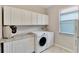 Bright laundry room with white cabinets, washer, dryer, and granite countertop at 16840 Whisper Elm St, Wimauma, FL 33598