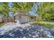 View of the home featuring brick accents, a one-car garage, and a spacious driveway with mature shade trees at 1710 S Lake Ave, Clearwater, FL 33756