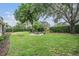 Well-maintained backyard with lush greenery, mature trees, and a stone fire pit at 19708 Wellington Manor Blvd, Lutz, FL 33549