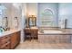 Bathroom features a soaking tub with tile surround, double vanity, makeup table and arched windows at 19708 Wellington Manor Blvd, Lutz, FL 33549